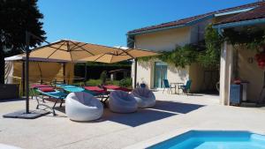 een patio met stoelen, een parasol en een zwembad bij Ursuslodge in Soustons