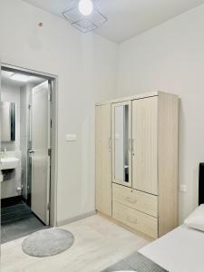 ein Schlafzimmer mit einem großen Holzschrank und einem Badezimmer in der Unterkunft Jesselton Quay by Adara Suites in Kota Kinabalu