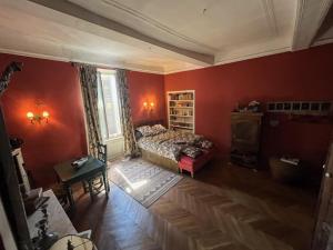a bedroom with red walls and a bed and a table at Chambre avec vue in Saignon
