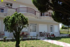 a house with red chairs and tables in a yard at Kondylenia Rooms in Loutrá Vólvis