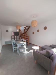 a living room with a couch and a table and chairs at La Maison de la Plage in Arromanches-les-Bains