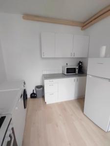 a kitchen with white cabinets and a microwave at La Maison de la Plage in Arromanches-les-Bains +4 photos