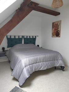 a bedroom with a large bed with a blue headboard at La Maison de la Plage in Arromanches-les-Bains