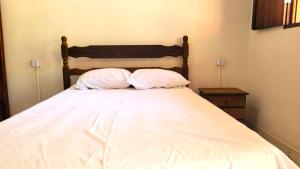 uma cama com duas almofadas num quarto em Chalé da Vó em Vargem Bonita