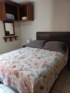 1 Schlafzimmer mit einem Bett mit Blumenbettdecke in der Unterkunft Agradable y cómodo departamento a 5 minutos del aeropuerto in Mexiko-Stadt