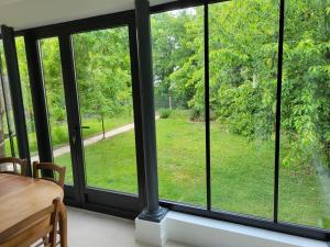 a room with glass windows with a table and a view at La maison des Sablons in Chartres