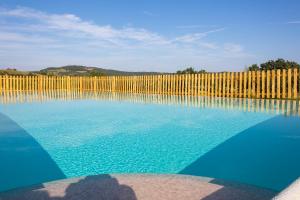 a pool of blue water with a wooden fence at La Poggiata in Monterotondo