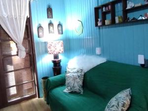 Un dormitorio con una cama verde y una lámpara en Pousada Atlântica stay home en Tramandaí