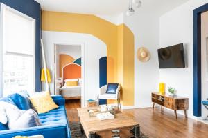 a living room with a blue couch and yellow accent wall at Royal Glam-Marilyn inspired 1BD - 30 Min to NYC in Edgewater