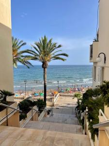 a view of a beach with a palm tree and the ocean at La Marina SeaView Penthouse in Sitges
