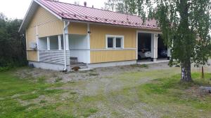 a yellow house with a tree in front of it at Asemansaunatupa in Pyhäjärvi