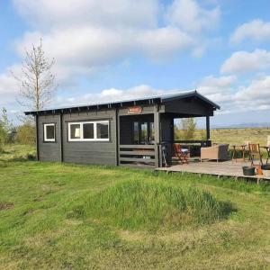 a small house with a deck in a field at Log house with a view - Bjalki in Hella