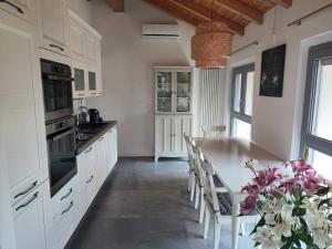 una cocina con armarios blancos y una mesa con sillas en Olia House, en Olginate