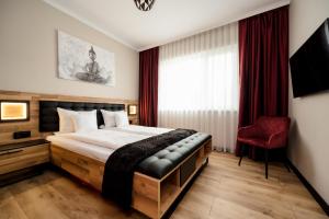 a bedroom with a large bed and a red chair at Backyard Jacuzzi House in Oradea