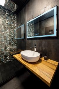 a bathroom with a white bowl sink on a wooden counter at Backyard Jacuzzi House in Oradea