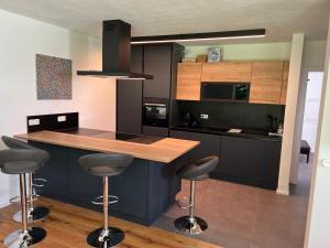 Lenzing的住宿－PR Arpartment，厨房配有黑色橱柜和带吧台凳的台面