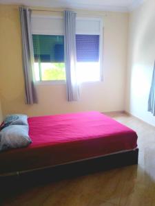 sypialnia z różowym łóżkiem i 2 oknami w obiekcie Résidence Nydia w mieście Ras El Ma