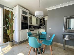 ラ・プラヤ・デ・アルグイネグインにあるSelena Luxury Monte Carreraのキッチン(ガラステーブル、青い椅子付)
