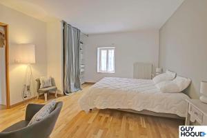 biała sypialnia z łóżkiem i krzesłem w obiekcie Le Moulin du Chardonnet w mieście Tramolé