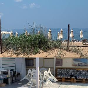 ein paar weiße Stühle am Strand in der Unterkunft Beach hub caravans Gradina in Tschernomorez