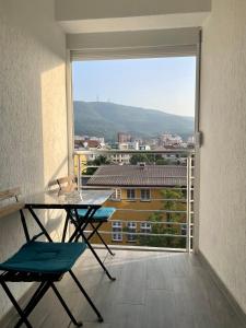 a balcony with a table and chairs and a large window at Gallery City Center Apartment in Skopje