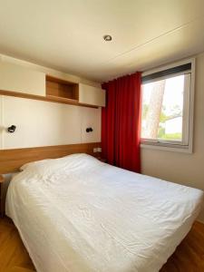 a bedroom with a white bed and a window at MOBIL HOME 6 personnes Cap Ferret in Lège-Cap-Ferret