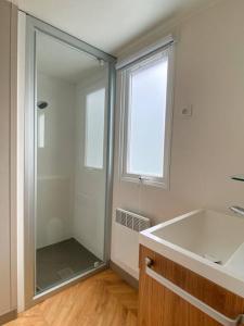 a bathroom with a shower and a tub and a window at MOBIL HOME 6 personnes Cap Ferret in Lège-Cap-Ferret