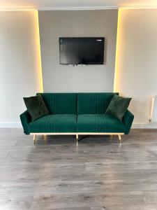 a green couch in a living room with a flat screen tv at Luxuries 2 Bed Room Flat in Canary Wharf in London