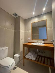 ein Badezimmer mit einem WC, einem Waschbecken und einem Spiegel in der Unterkunft Villa Maihue departamentos de montaña - Caviahue in Caviahue