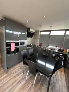 eine Küche mit einem schwarzen Tisch und schwarzen Stühlen in der Unterkunft 6 Bed 6 Bath House Fantastic for contractors & Groups in Luton
