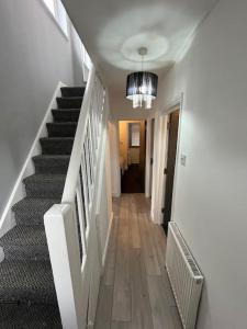 einen Flur mit Treppe und Kronleuchter in einem Haus in der Unterkunft 6 Bed 6 Bath House Fantastic for contractors & Groups in Luton