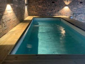 Edwardian Manor near Glasgow City with HEATED POOL & HOT TUB في Giffnock: مسبح كبير في غرفة بجدار من الطوب