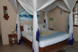 Driftwood Beach Lodge في جامبياني: غرفة نوم بسرير مع مظلة