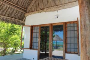 an open door of a house with a view of the ocean at Driftwood Beach Lodge in Jambiani