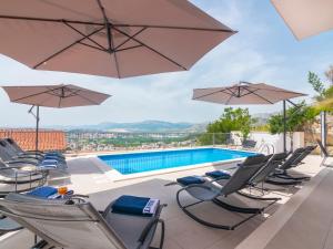 a group of chairs and umbrellas next to a swimming pool at Apartments L&L in Podstrana