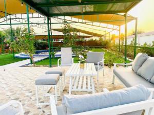 eine Terrasse mit Sofas, einem Tisch und Stühlen in der Unterkunft Luxury Farm 2 with Swimming Pool in Al Rahba