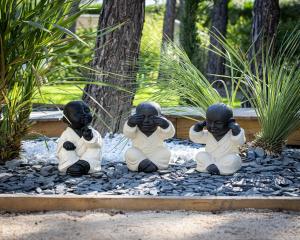 tres niños sentados en las rocas en un jardín en LES LODGES TAIZEN, séjour SPA- sans enfants en Saint-Cannat