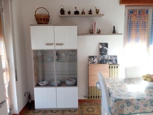 un armadietto bianco in una cucina con tavolo di Casa vacanze Il Carrubo a Leporano