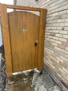 a wooden door with the on it next to a brick wall at No 64 Bed and Breakfast in Lymington