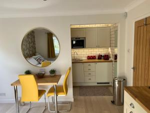 a kitchen with a table and yellow chairs and a mirror at No 64 Bed and Breakfast in Lymington