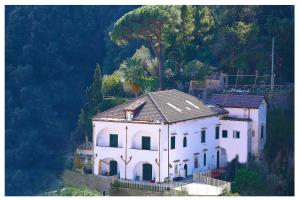 una gran casa blanca en una colina con árboles en Villa Lara Hotel en Amalfi