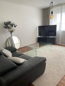 - un salon avec un canapé noir et une table en verre dans l'établissement CHALET_3 Design Appartments, à Waldbüttelbrunn