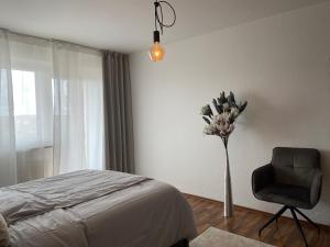 - une chambre avec un vase de fleurs et une chaise dans l'établissement CHALET_3 Design Appartments, à Waldbüttelbrunn