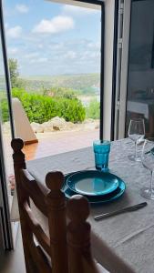 a table with a plate and wine glasses on it at Modernes Apartment mit traumhaftem Blick Vistamar3 in Cala'n Porter
