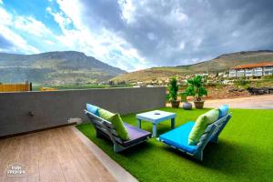 a patio with a table and chairs on a green lawn at Yalarent Melody- Suites with privat pools in Migdal