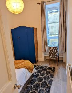 - une chambre avec une armoire bleue et une fenêtre dans l'établissement Cozy Room Close To The City, à Édimbourg