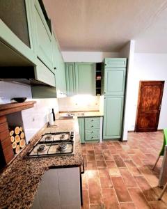 a kitchen with green cabinets and a stove top at Nel centro storico di Trequanda in Trequanda