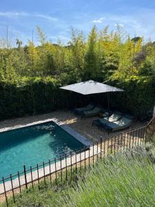a pool with an umbrella and two chairs and a table at Villa de charme, avec piscine, 6 personnes in Éguilles