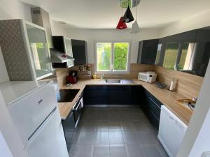 uma cozinha com armários pretos e um frigorífico branco em Vue sur Mer em Criel-sur-Mer