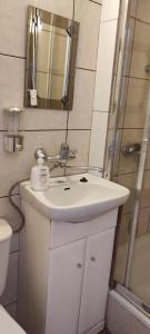 een badkamer met een witte wastafel en een douche bij Słoneczna in Grzybowo